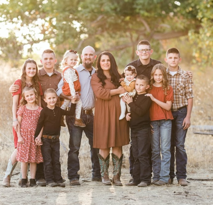 Nathaniel and Ashley Ashby with their eleven children, photographed outdoors